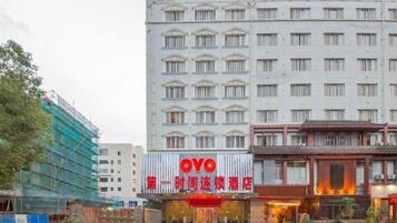 A hotel with a prominent red sign, a traditional architectural style, and a modern building in the background.