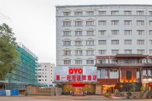 A hotel with a prominent red sign, a traditional architectural style, and a modern building in the background. - The First Time Hotel (Yueqing)