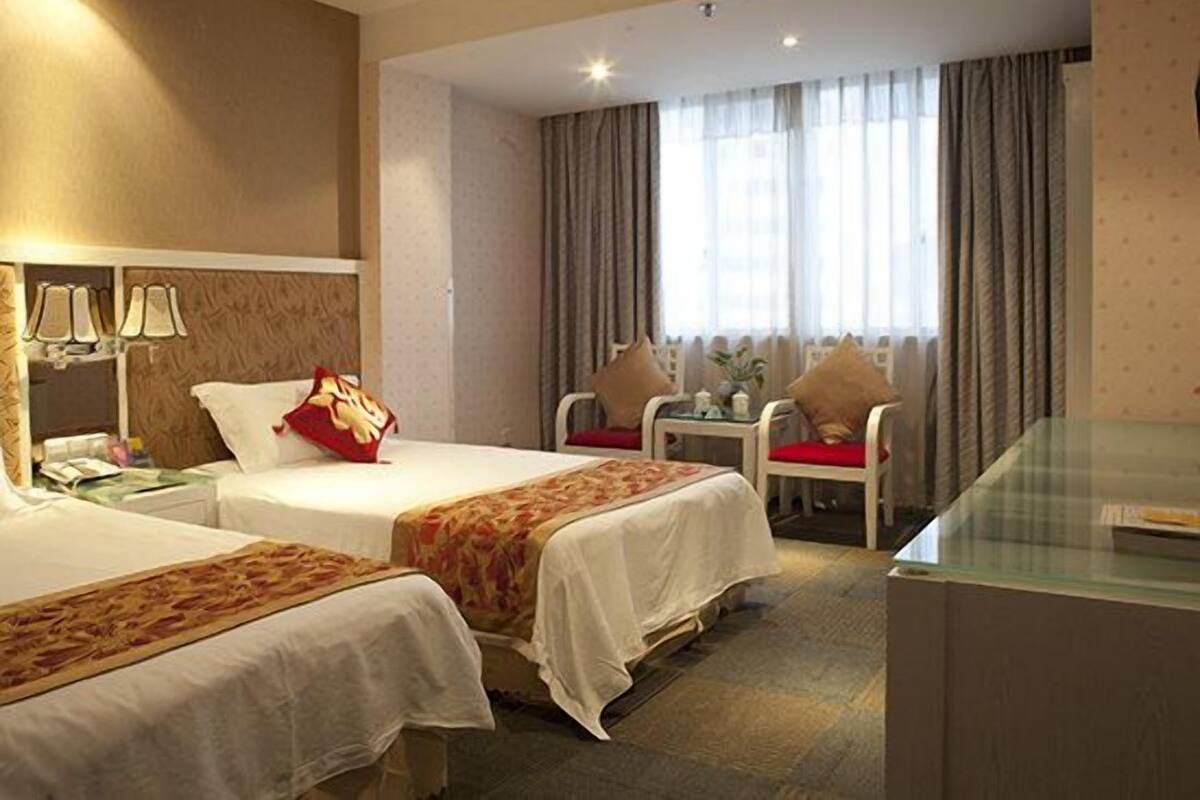 Ein Hotelzimmer mit zwei Betten, einem Schreibtisch und einem Stuhl.