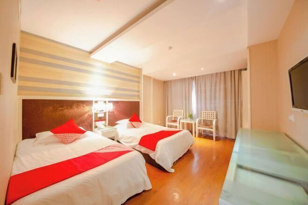 Ein Hotelzimmer mit zwei Betten, einem Schreibtisch, einem Stuhl und einem Fernseher.