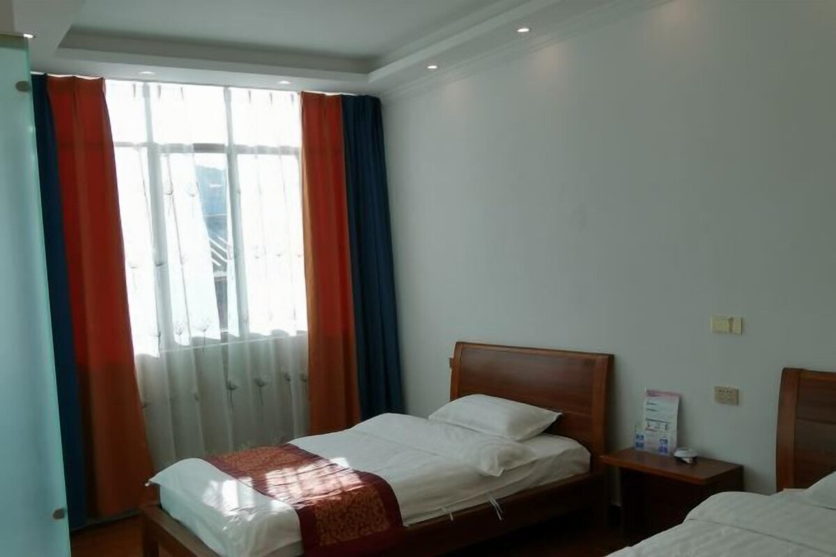 Habitació d'hotel amb llit, una tauleta de nit i una finestra amb cortines.