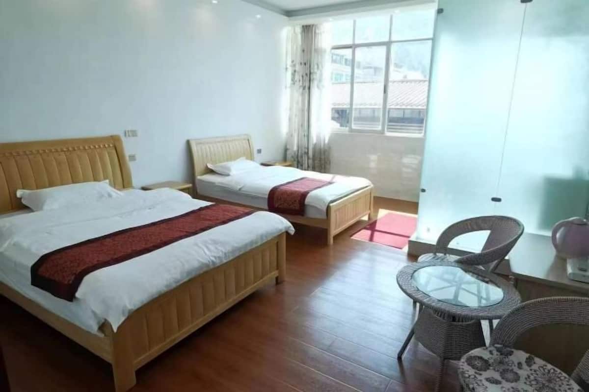 Habitación de hotel con dos camas, una mesita pequeña y una silla.