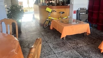 A room with a wooden table, a bicycle, and a kitchen area with a counter.