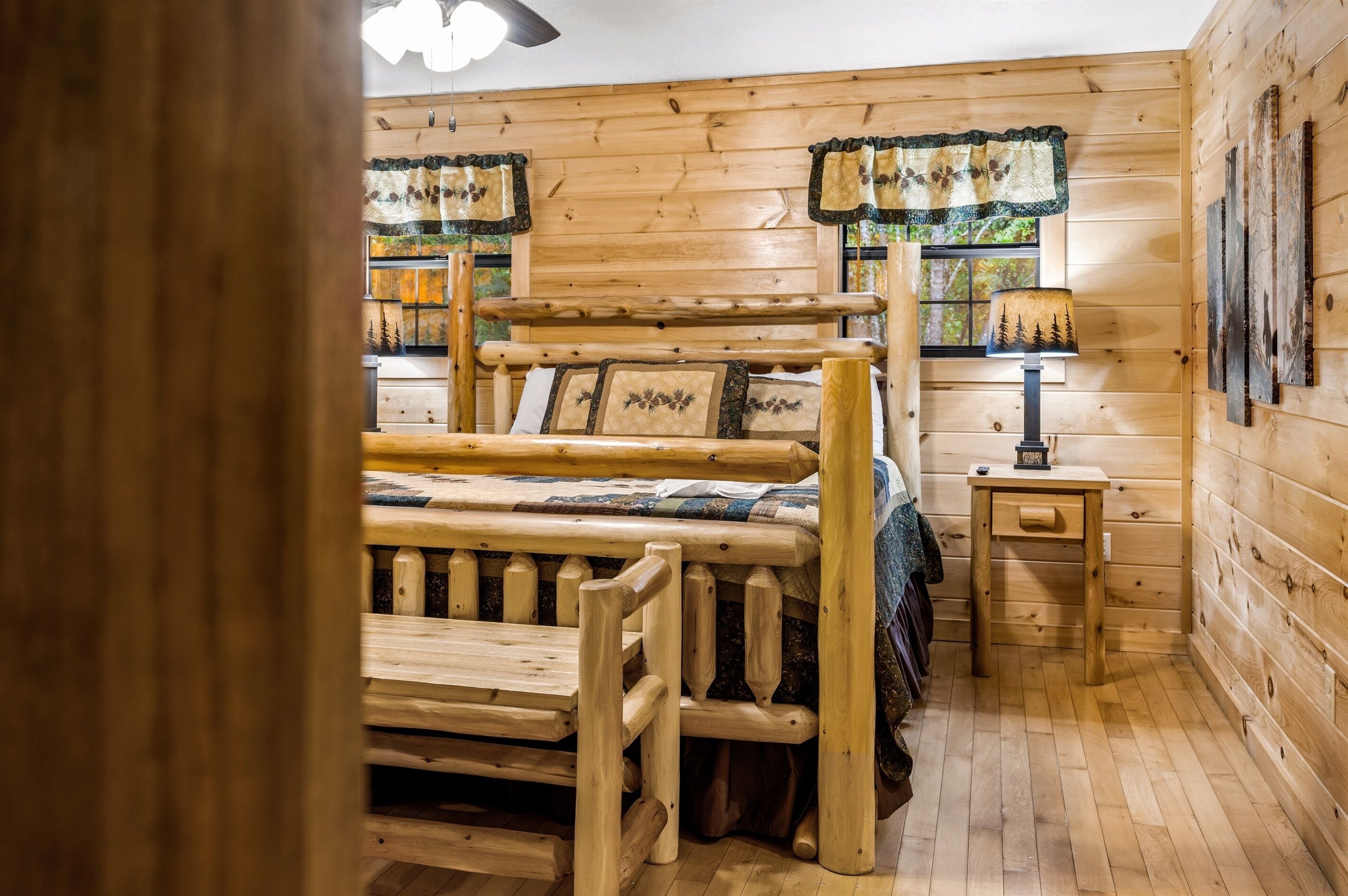 Une chambre dans un chalet en bois, avec un lit, une petite table et une lampe.