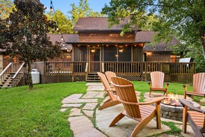 A wooden deck with Adirondack chairs and a fire pit, surrounded by a wooden fence and a stone pathway. - Pure Cabin Serenity Awaits – Book Your Escape! (Sevierville)