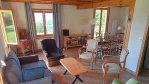 A spacious living room with a sofa, armchairs, a coffee table, and a dining area with chairs and a table.