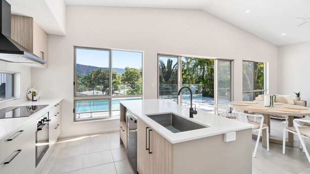 A modern kitchen with a large island, a built-in oven, and a view of a pool and mountains. - Belle Escapes Sea La Vie (Trinity Beach)
