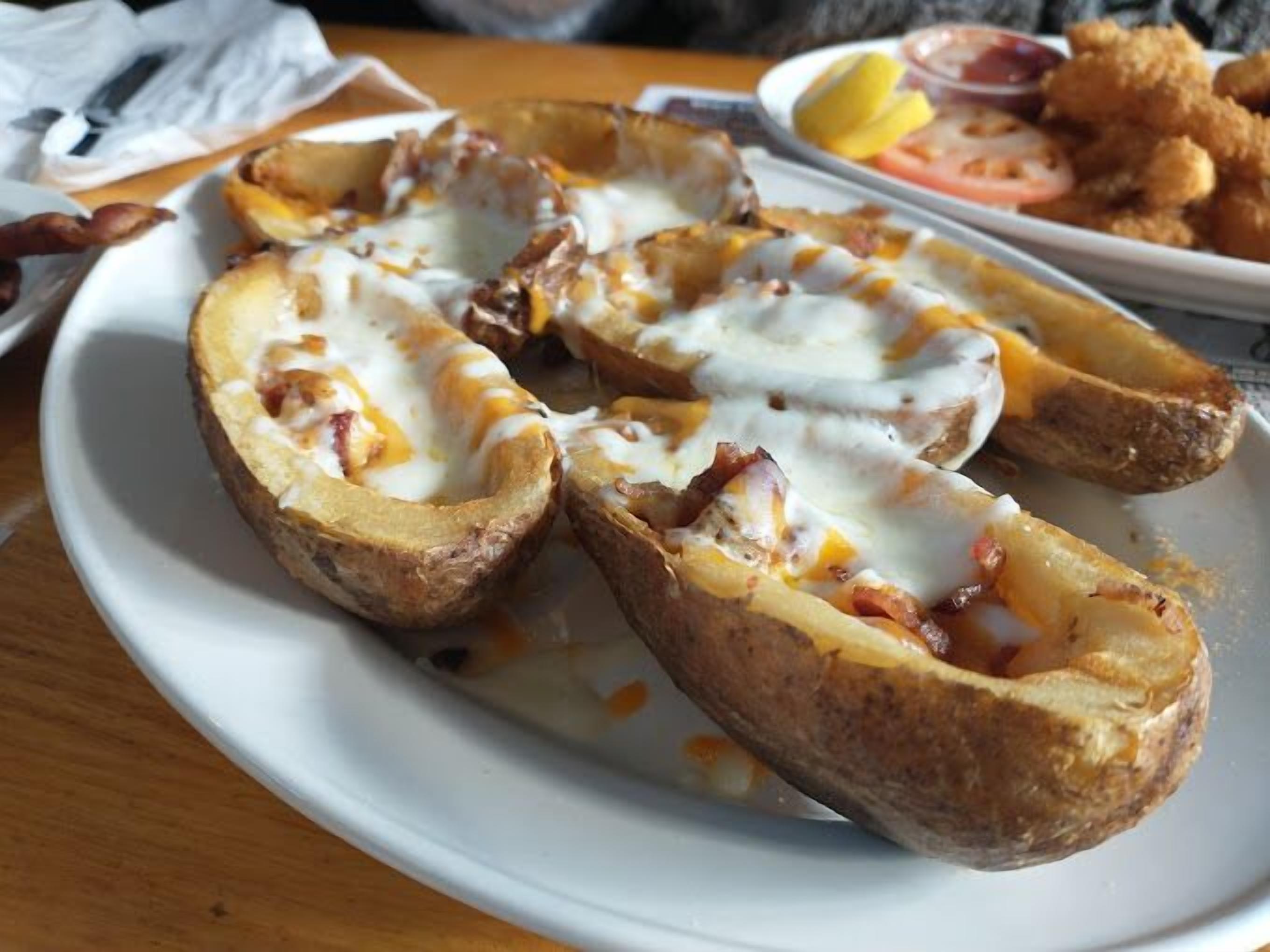 A plate of baked potatoes topped with melted cheese and bacon.