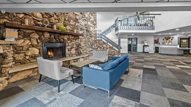 A spacious lobby with a stone wall fireplace, a blue sofa, and a checkered floor.