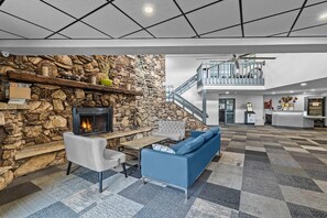 A spacious lobby with a stone wall fireplace, a blue sofa, and a checkered floor.