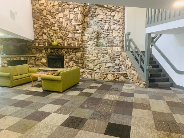 Un salon avec un mur en pierre, une cheminée, un canapé et un escalier.