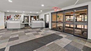 A reception area with a check-in counter, a waiting area with a patterned carpet, and an exit door.