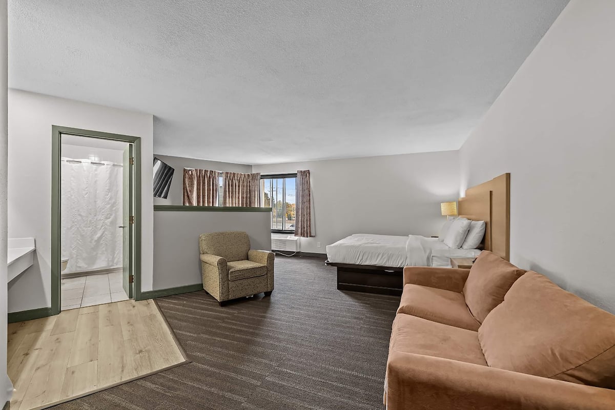 Una habitación de hotel con una cama, un sofá, una silla y una pequeña mesa.