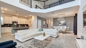 Un salón amplio con un sofá blanco modular, una mesa de centro y un comedor con mesa y sillas blancas.
