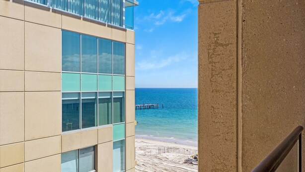 A modern building with large windows overlooking a beach and a pier.
