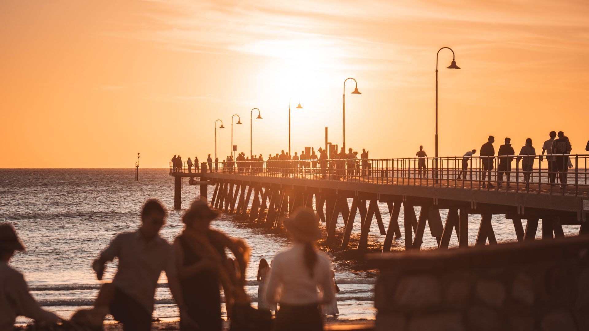 A pier extending into the water with people walking along it.