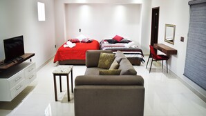 Un dormitorio moderno con una cama, dos mesitas de noche, un televisor, un sofá y un escritorio.