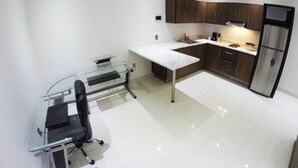 Una cocina moderna con una mesa de comedor de vidrio, armarios de madera oscura y un refrigerador de acero inoxidable.