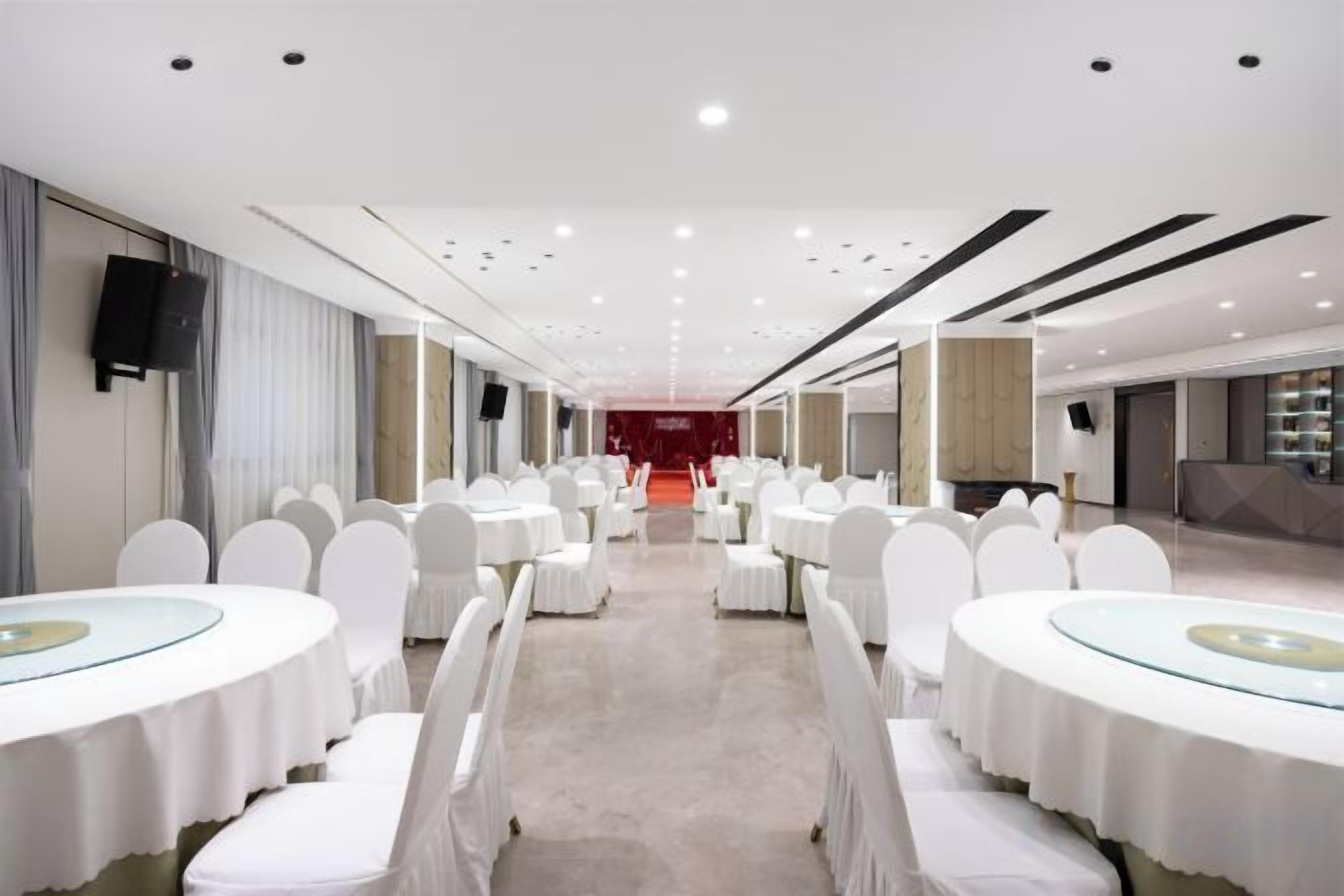 Una sala da banchetto con tavoli rotondi e sedie, un palco e una moquette rossa.