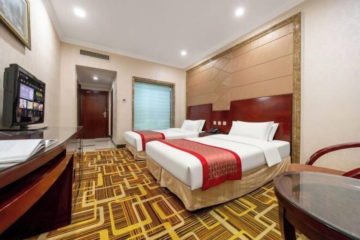 A hotel room with two beds, a desk with a computer, and a TV.