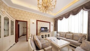 A spacious living room with a sofa set, a coffee table, a television, and a chandelier.