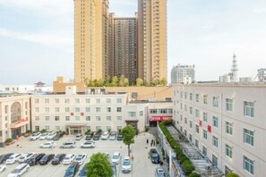 Eine mehrstöckige Parkgarage mit in Reihen geparkten Autos, neben einem Gebäude mit einer roten Beschilderung.