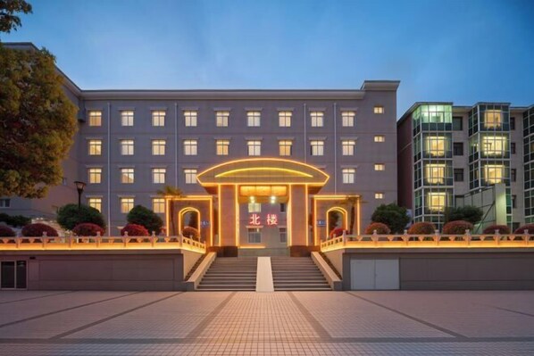A multi-story hotel with a central entrance, a staircase, and a well-lit facade. - Qingping Hotel (Xinmi)