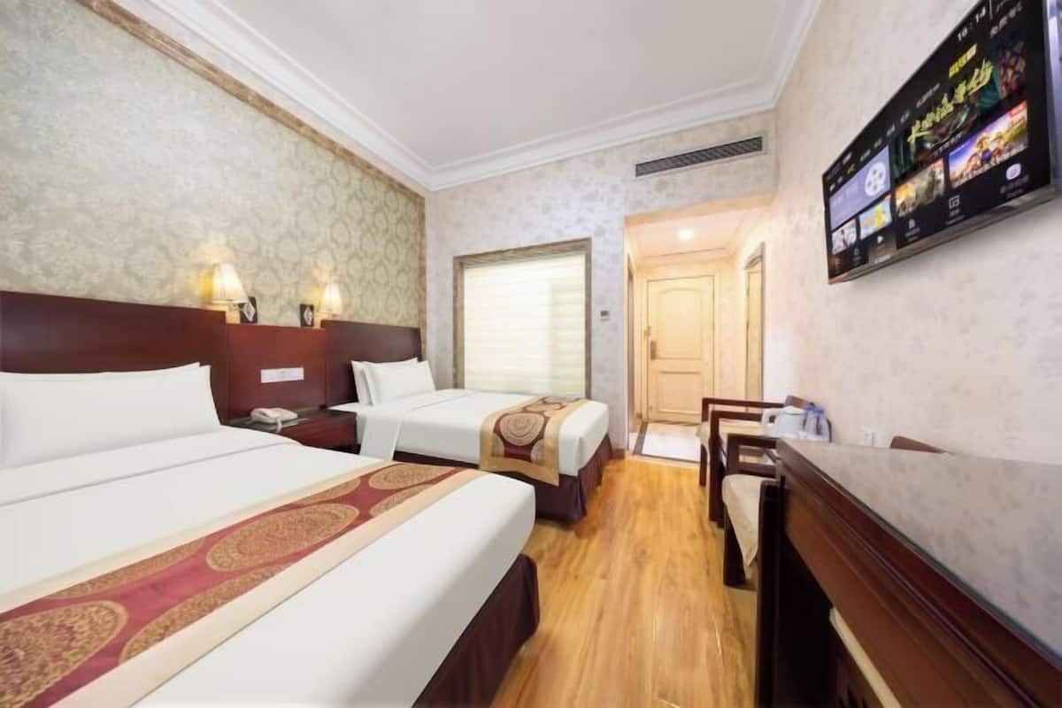 A hotel room with two beds, a TV, a desk, and a chair.
