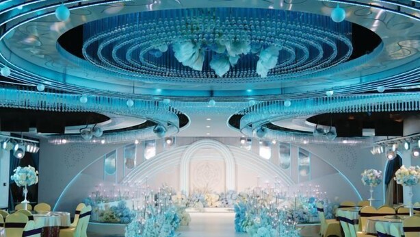A luxurious venue with a central aisle, elegant floral arrangements, and a sophisticated ceiling design.