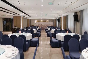 A conference room with rows of tables and chairs, a stage at the front, and a staircase to the left. - Qingping Hotel (Xinmi)