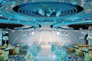 A grand hall with a central aisle, chandeliers, and floral arrangements. - Qingping Hotel (Xinmi)