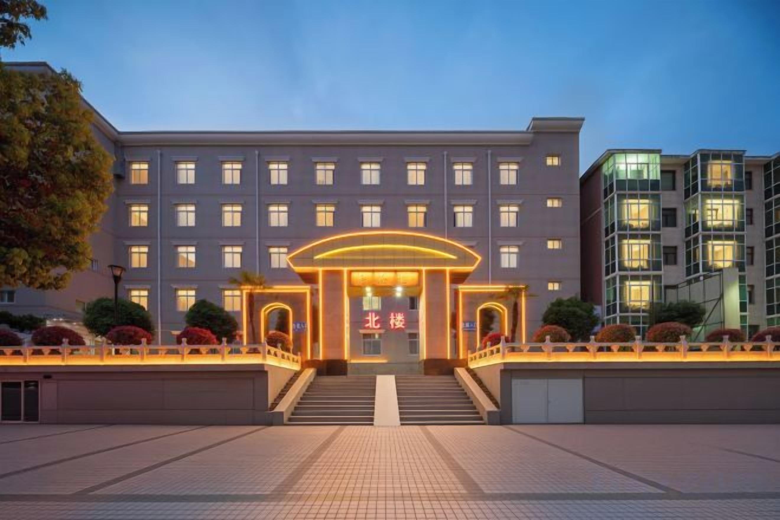 A hotel entrance with a central archway, multiple floors, and a well-lit facade.