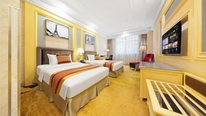 A hotel room with two beds, a desk, a TV, and a large window.