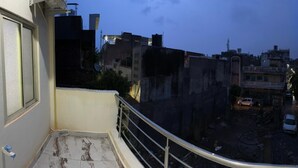 A balcony with a view of a city street at dusk. - BSSN Guest House (Gwalior)