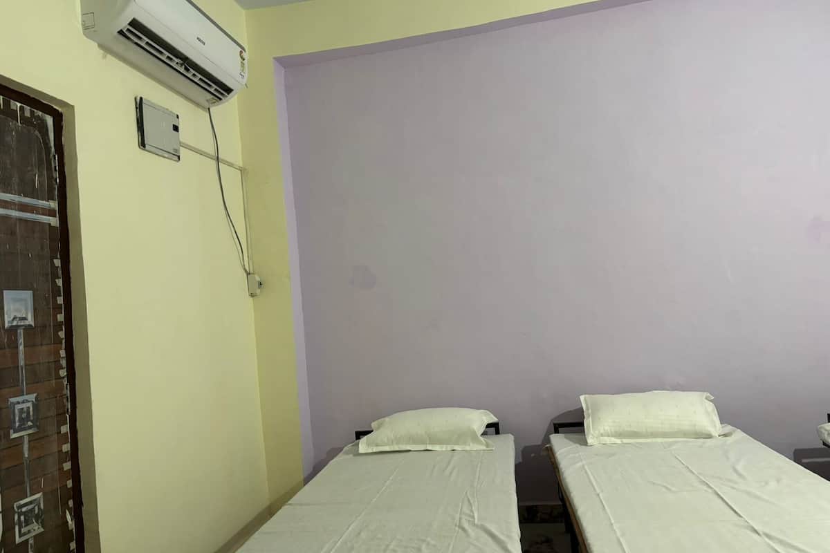 Une chambre avec deux lits, un appareil de climatisation et une porte avec une fenêtre.