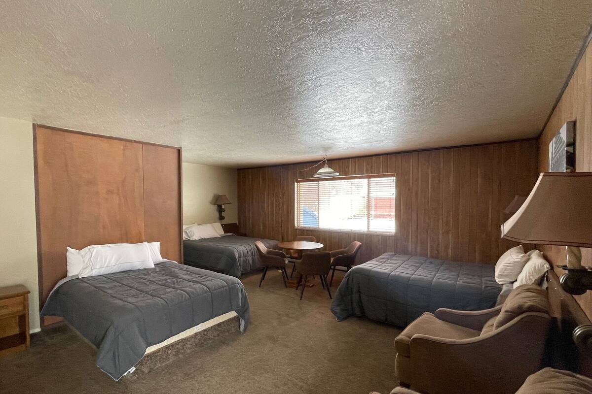 A room with two beds, a small table, and a chair.