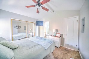Ein Schlafzimmer mit Bett, Schminktisch, Spiegel und Deckenventilator.
