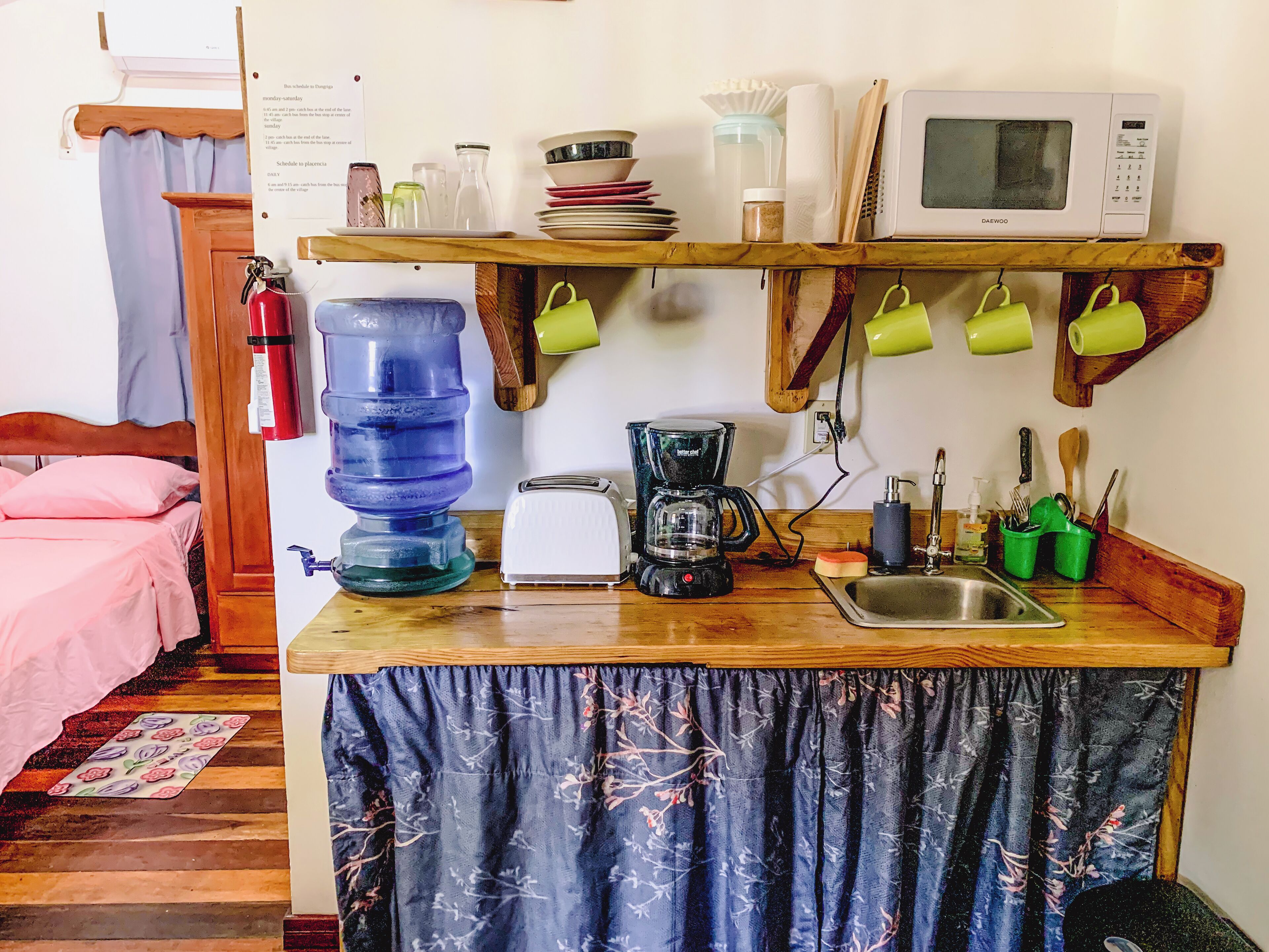 A compact kitchen with a microwave, toaster, coffee maker, and a sink.