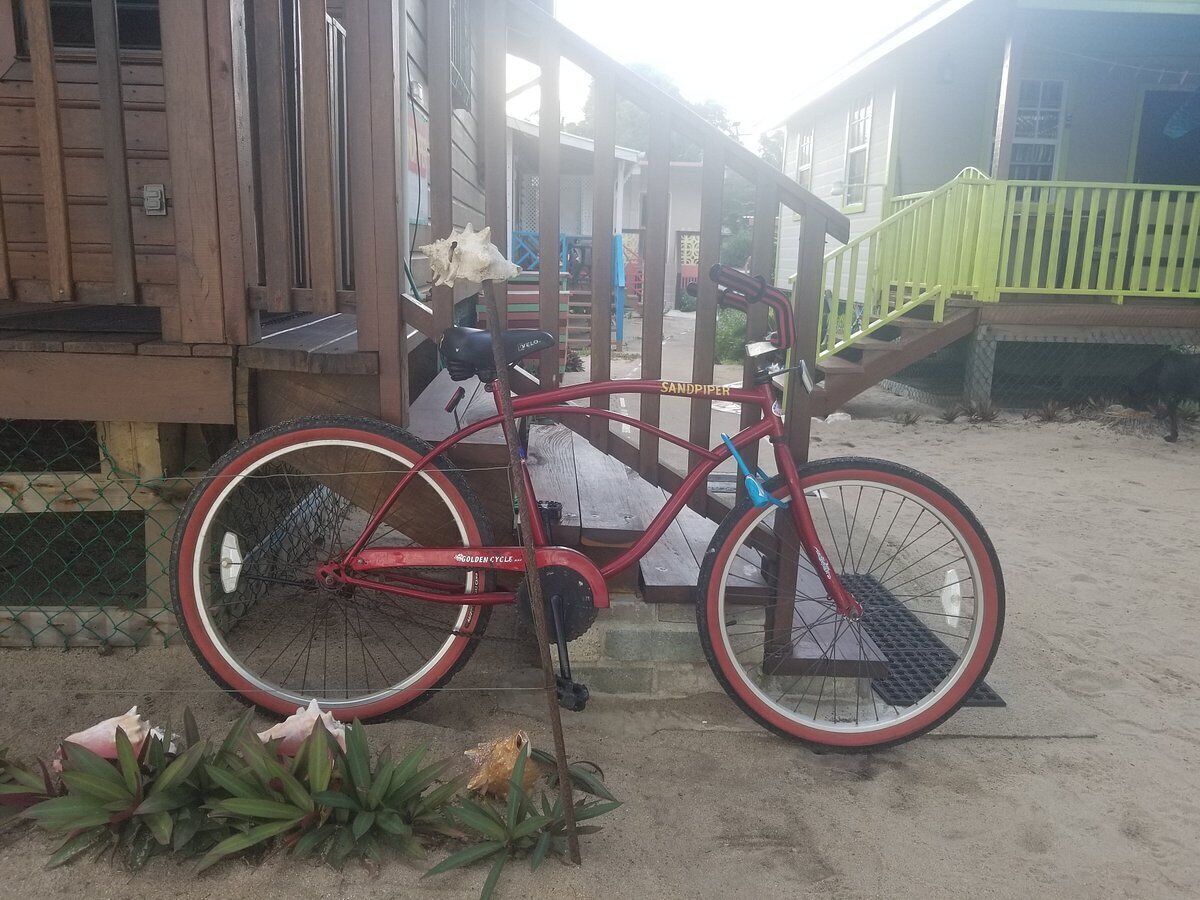 Una bicicleta roja estacionada en un muelle de madera con barandilla verde.