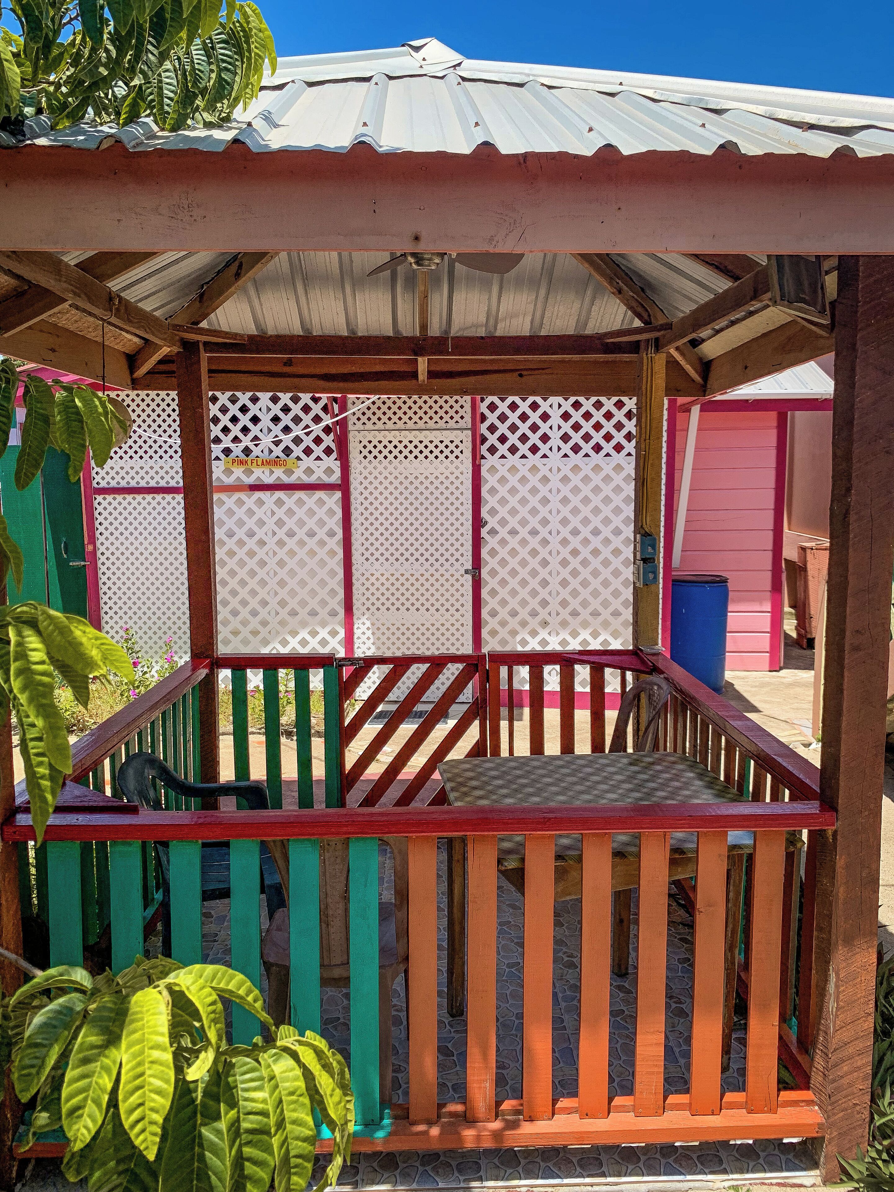 A covered outdoor seating area with a wooden bench and a metal roof.
