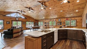 A spacious cabin interior with a large living area, a dining area, and a kitchen with wooden cabinetry and a central island.