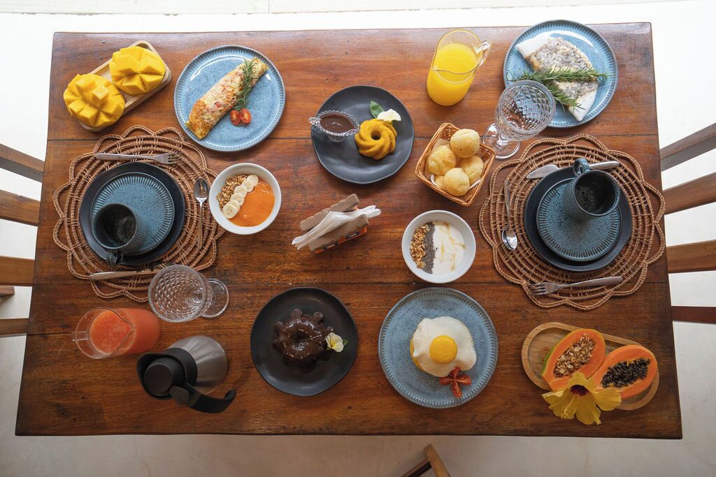 Une table en bois sur laquelle sont disposés divers aliments pour le petit-déjeuner, notamment des œufs, des toasts et des fruits.