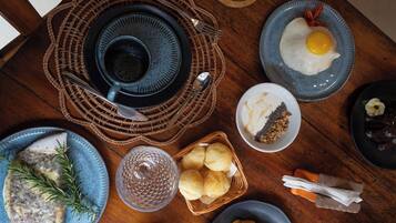 A breakfast setting with plates of food, a cup, and a basket of bread.