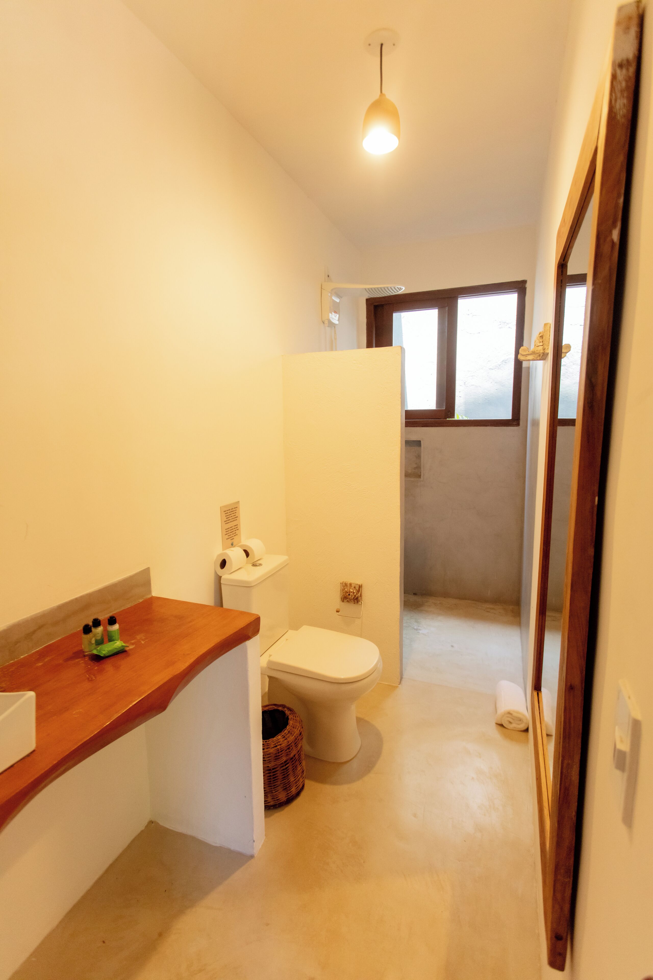 Un baño pequeño con encimera de madera, inodoro y zona de ducha.
