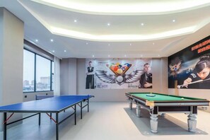 A billiards room with a pool table, a ping pong table, and a mural on the wall. - Golden Dragon Hotel (Red River Maitreya Branch) (Mile)