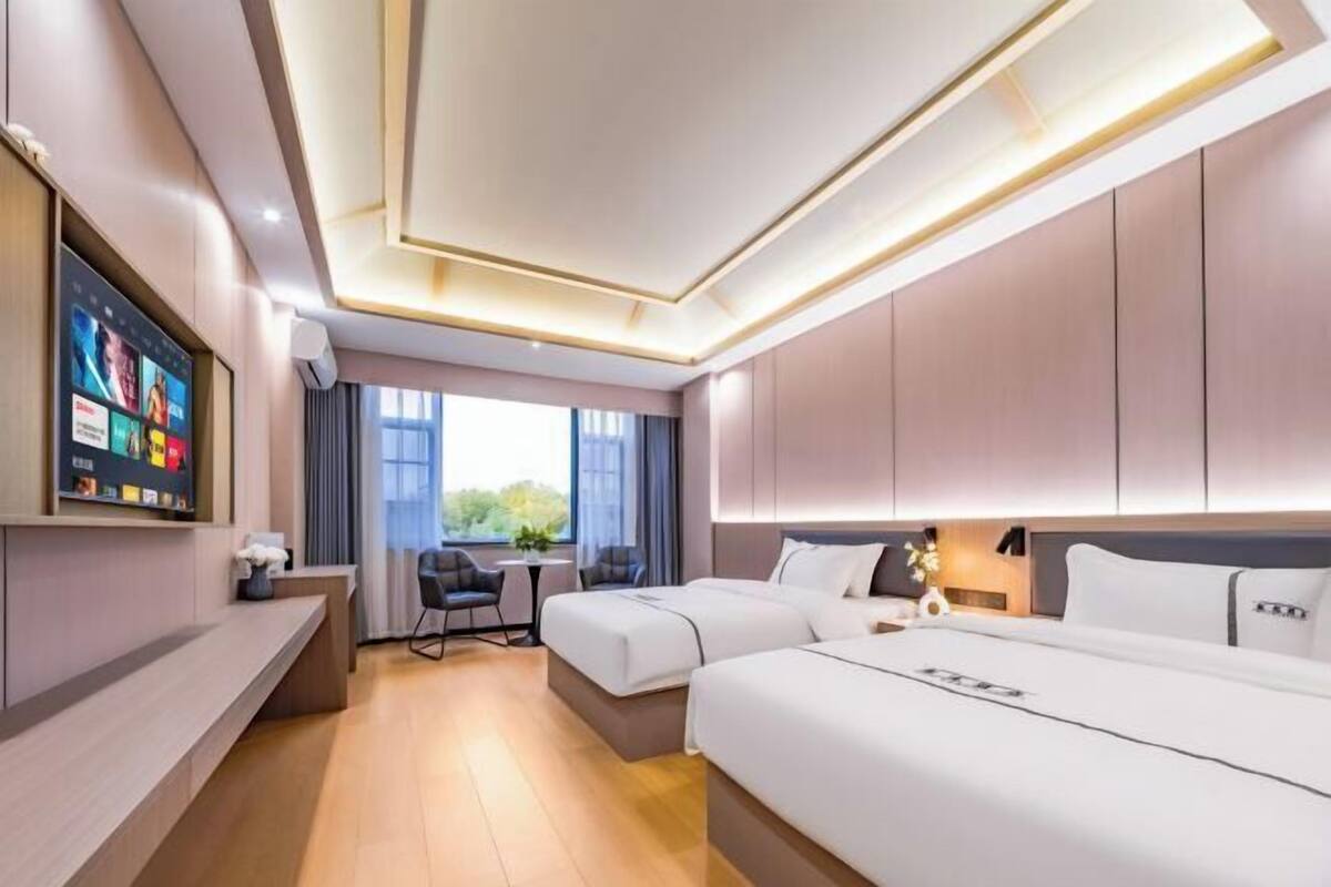Ein Hotelzimmer mit zwei Betten, einem Schreibtisch, einem Fernseher und einem Fenster mit Blick.