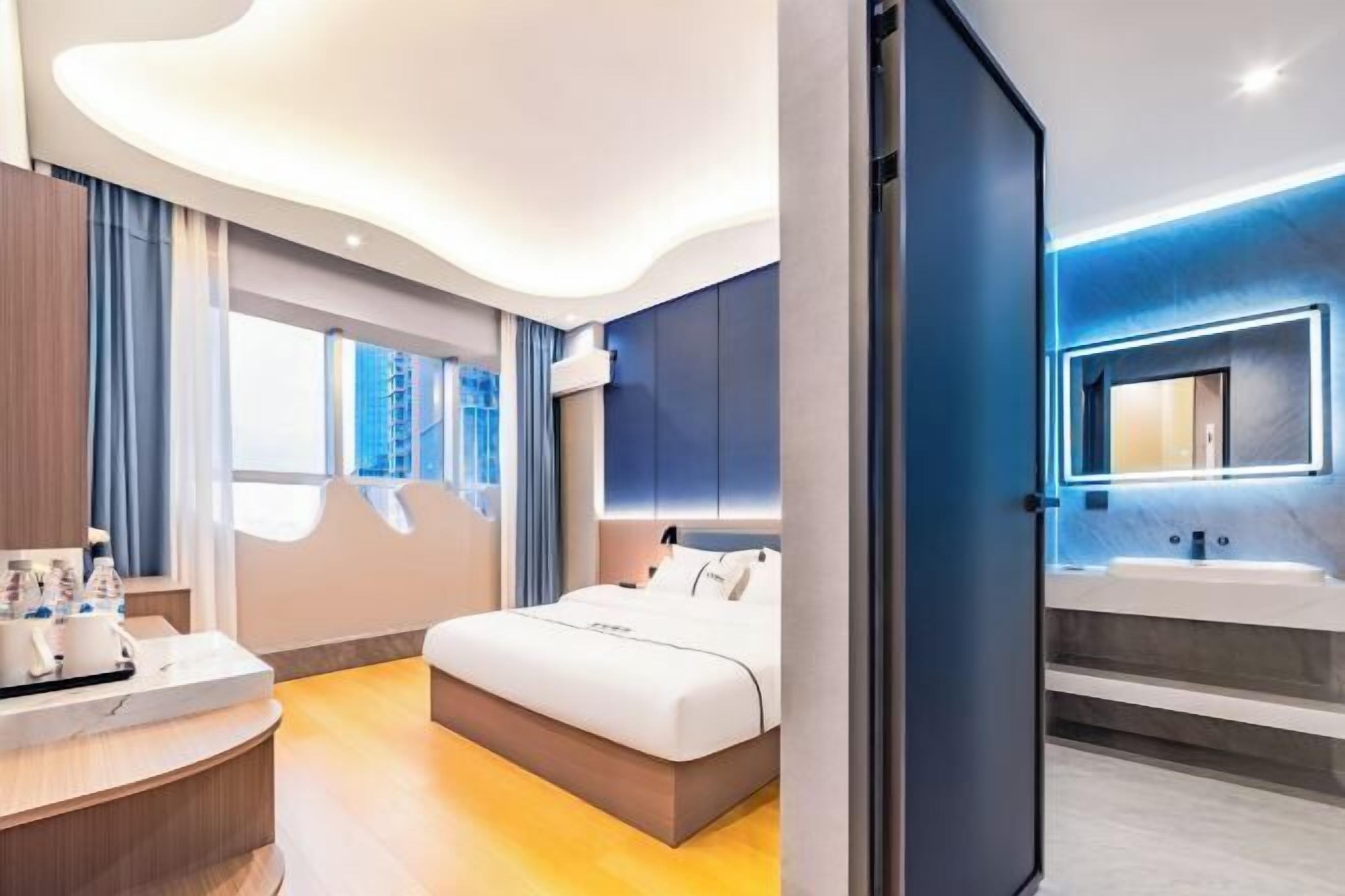 Habitación de hotel moderna con techo curvo, una cama grande, baño con espejo y vistas al exterior.