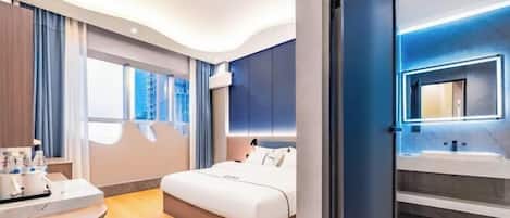 A modern hotel room with a curved ceiling, a large bed, a bathroom with a mirror, and a view of the outside.