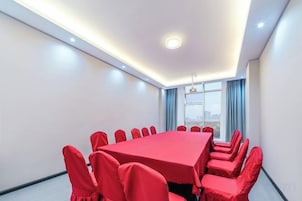 A conference room with a long table and chairs, a window with curtains, and a ceiling light.