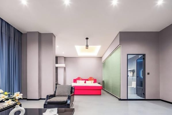 A modern hotel room with a seating area, a red sofa, and a glass partition. - Golden Dragon Hotel (Red River Maitreya Branch) (Mile)